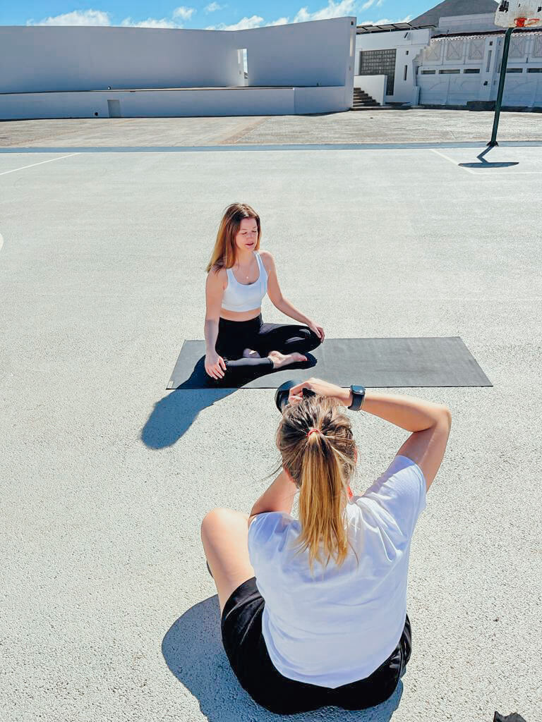Die Fotografin Mirjam Kilter sitzt auf dem Boden und fotografiert eine Yogalehrerin
