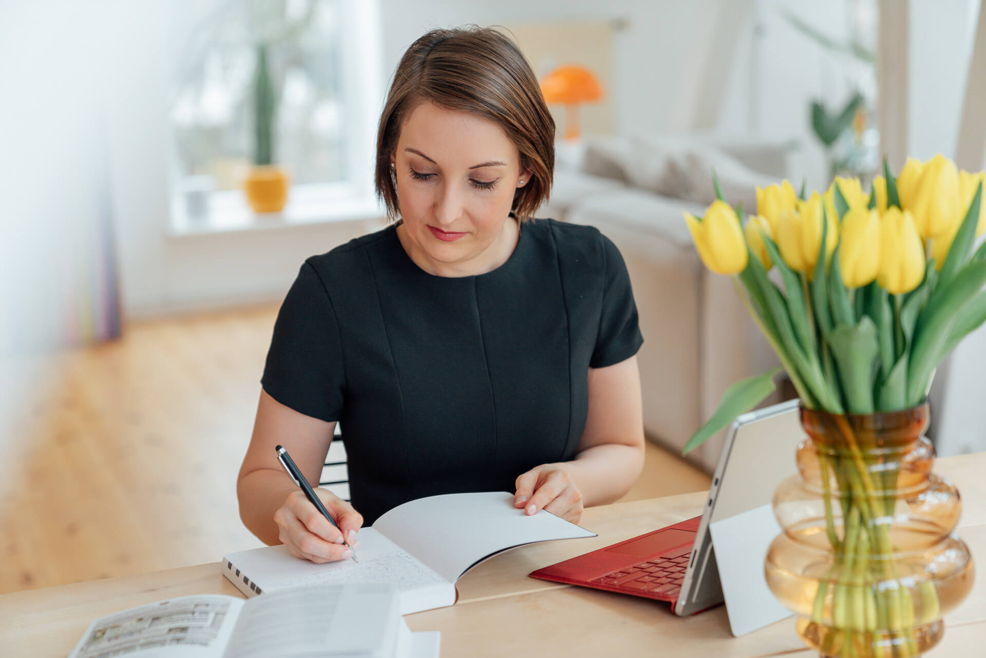 Arbeitssituation einer Frau die in ihr Notizbuch schreibt, das Foto ist während eines Brand Shoots entstanden. 