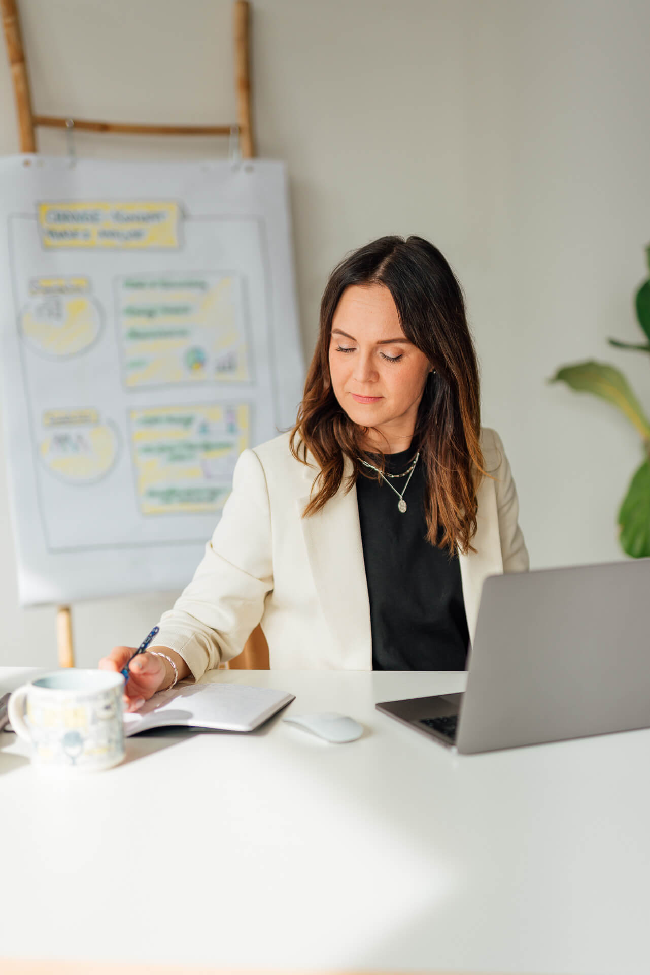 Businessportrait einer Frau die am Schreibtisch arbeitet, sie hat dabei den Laptop aufgeklappt.