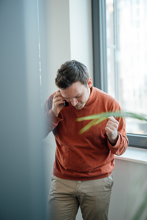 Businessportrait-Mann-Hamburg-mobil Ein Mann telefoniert und freut sich über etwas, das Bild ist ein gutes Beispiel für ein authentisches Businessfoto.