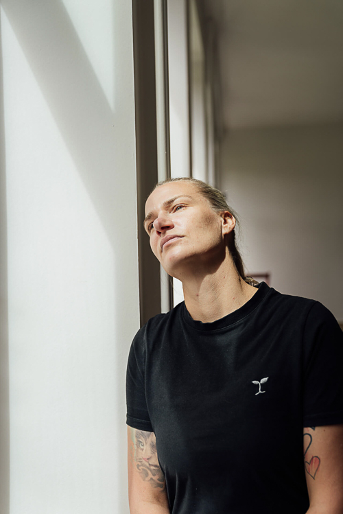Eine Frau lehnt am Fensterrahmen und schaut raus während eines Brandshootings