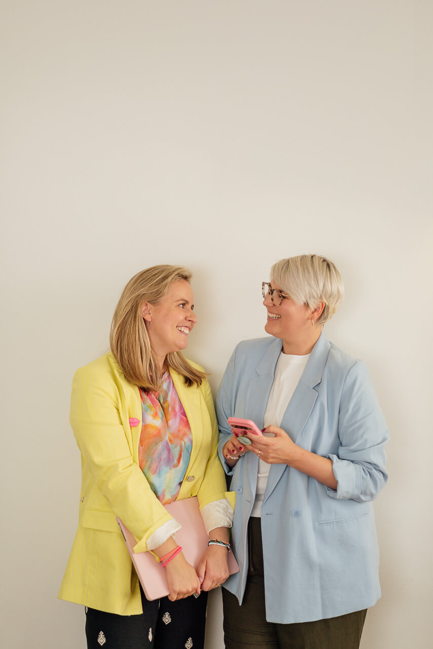 Portrait von Sonja und Melanie, die beide an der Wand stehen und sich anlachen