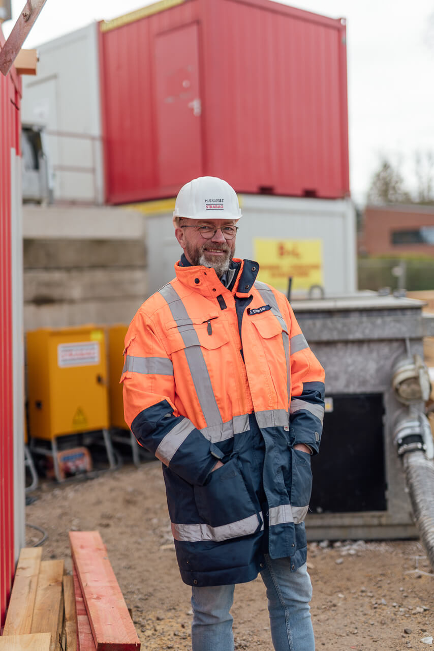 Portrait des Bauleiters auf der Baustelle in Arbeitsklamotten