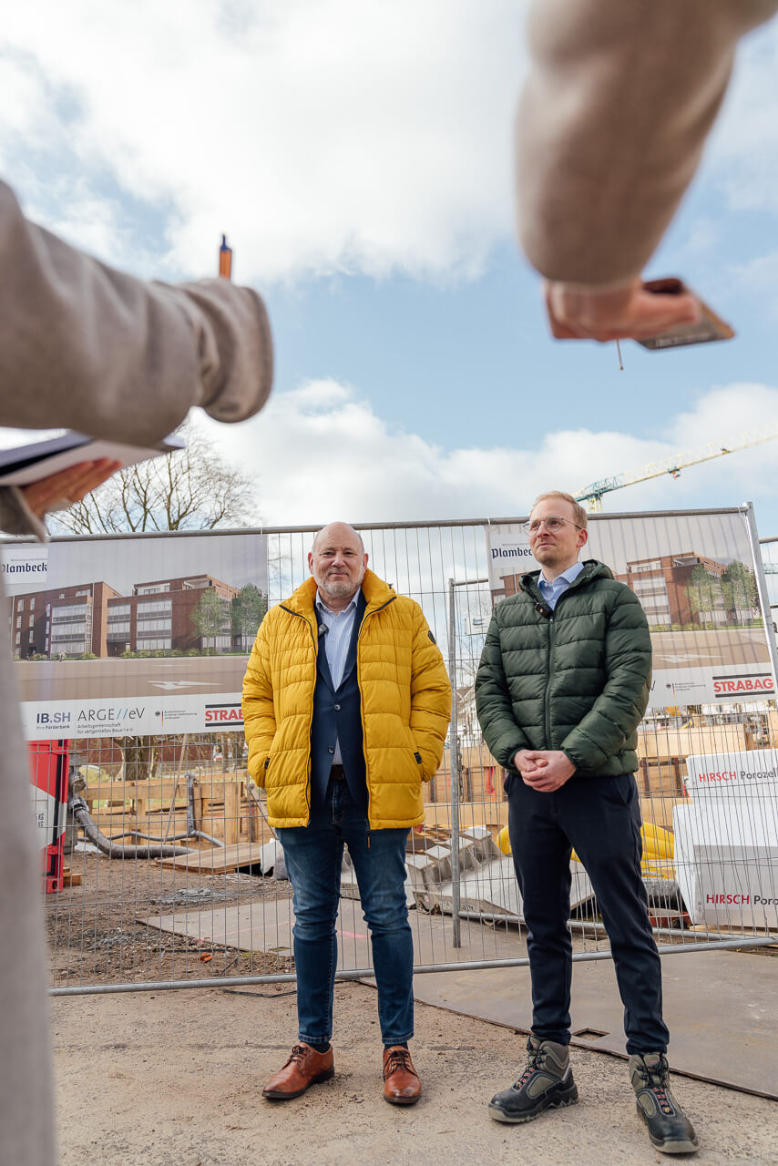 Portrait von Interimsmanager Wolfgang, der an der Wand lehnt und in einem gelben Pulli in die Kamera schaut. Das Bild ist während eines Brand Shoots entstanden. 
