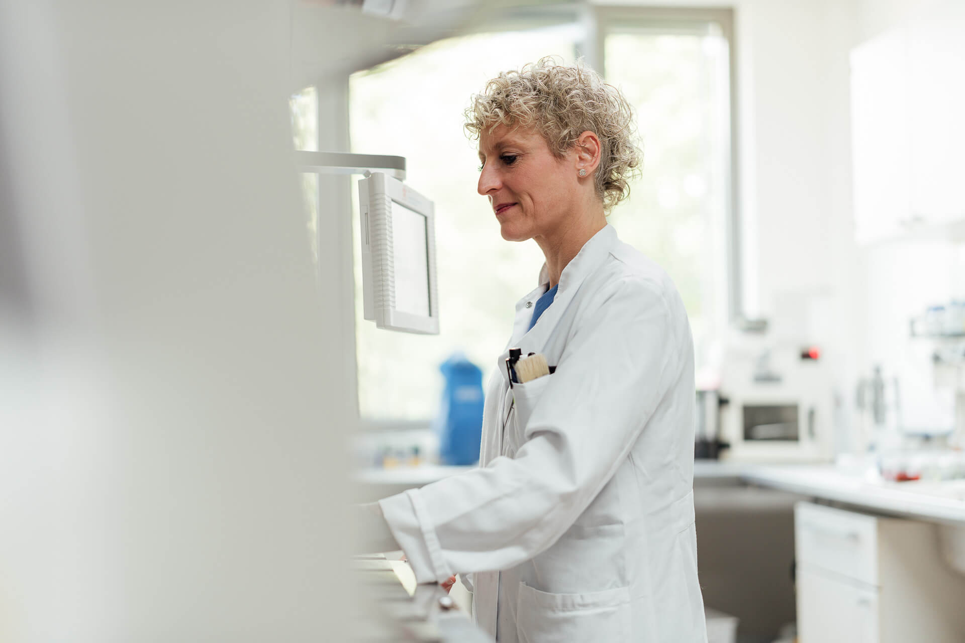 Portrait einer Medizinische Technologin für Laboratoriumsanalytik während sie den Färbeautomaten bedient