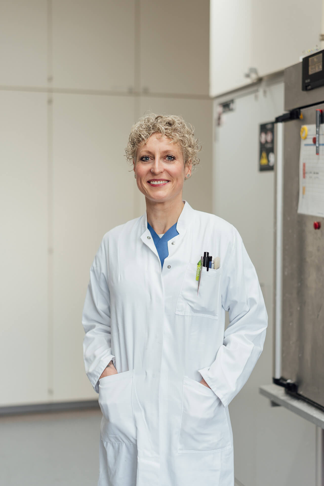 Reportage-Pathologin-web-2 Eine Frau während eines Personal Brand Shoots. Sie hat einen lila Blumenstrauß in der Hand und lacht herzlich in die Kamera.