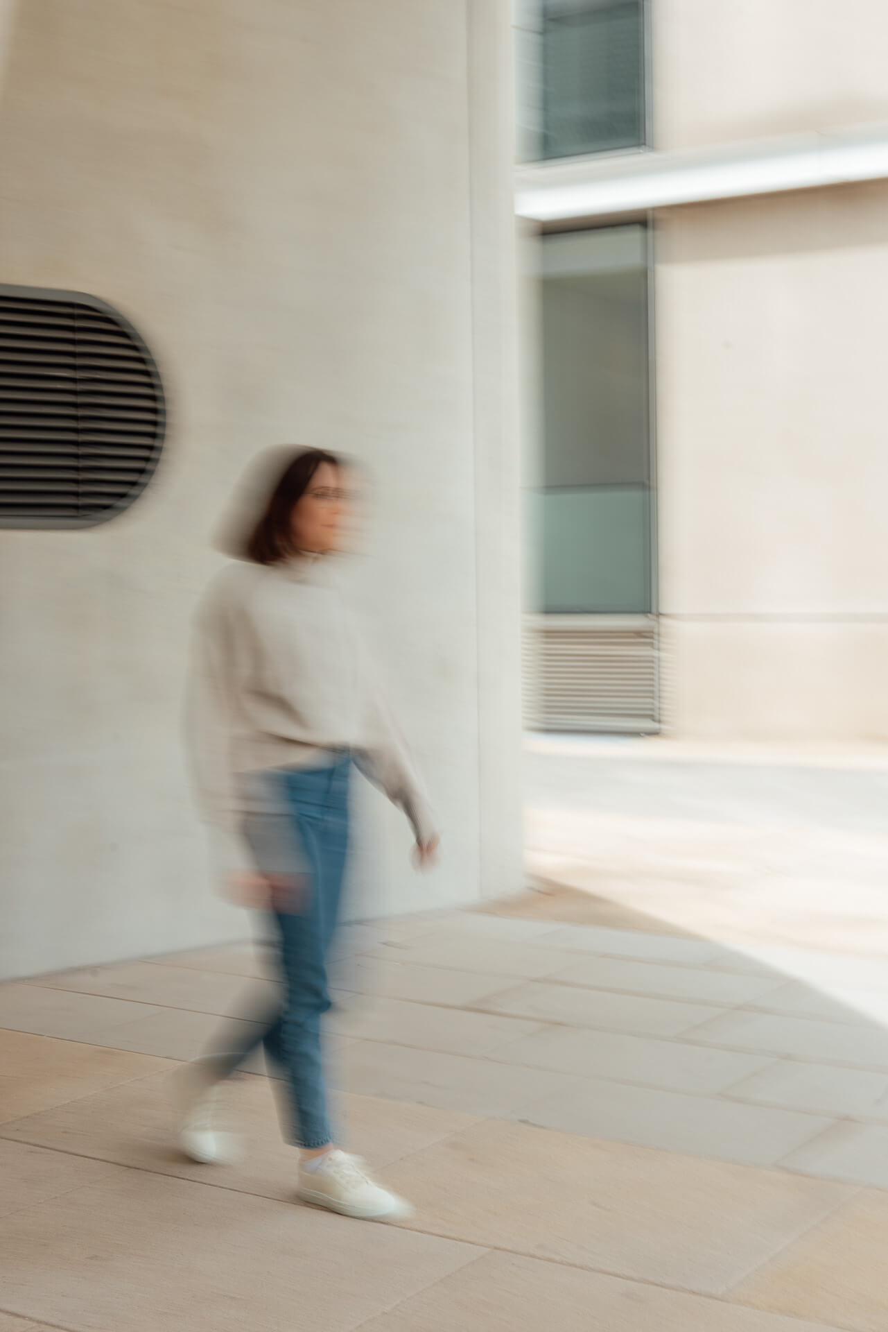 Ganzkörper Portrait einer Frau die an einer Wand lehnt, dabei wurde durch die Fensterscheibe fotografiert. Das Bild ist während eines Brand Shoots entstanden. 