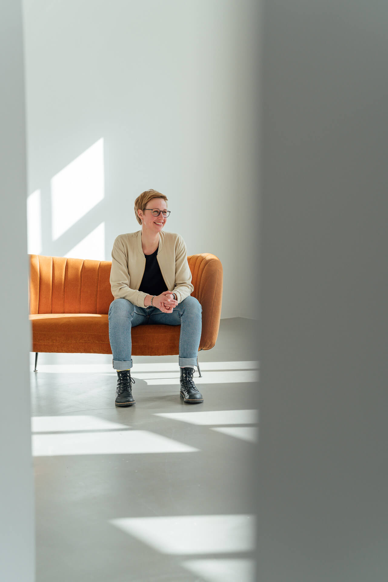 Studio-Days-Hamburg-Beispielbild-Franziska-Fotografin Portrait einer Frau, die auf einem orangenen Sofa sitzt.