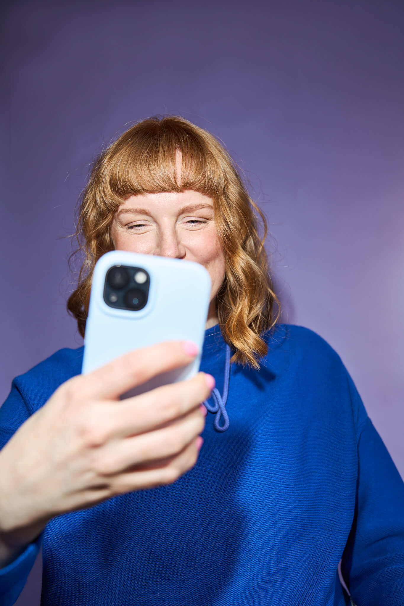 Eine Frau sitzt lachend auf dem Boden in Jeans und weißer Bluse. Das Bild ist ein schönes Beispiel für ein Businessfoto, das die Persönlichkeit zeigt.