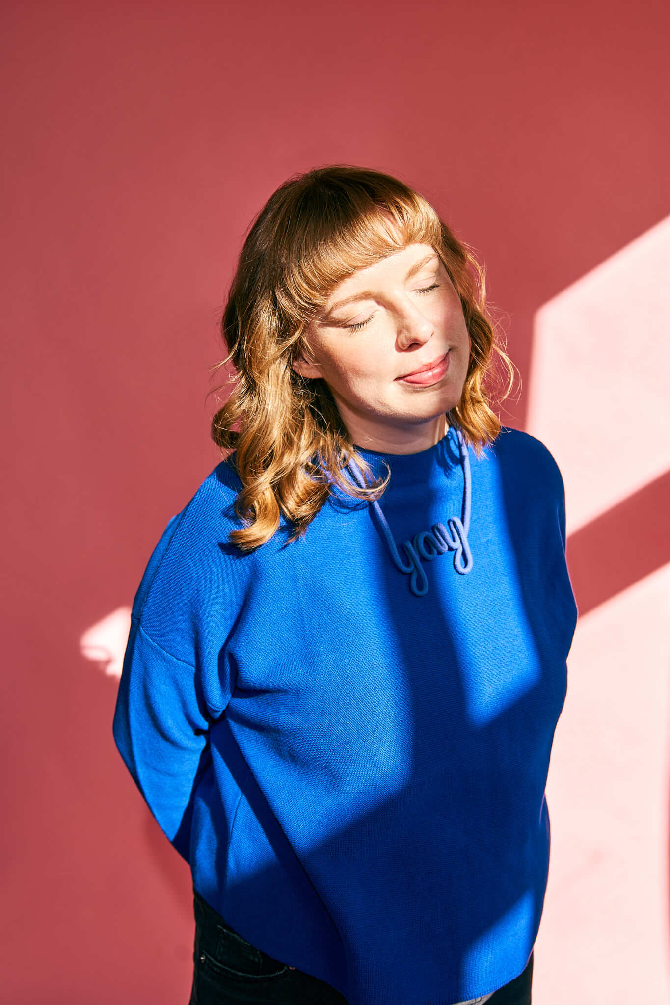 Personal-Brand-Designerin-Markenberatung-2 Personal Branding Fotografie für eine Frau, sie lehnt an der Wand, hat die Hände in den Taschen und ein lockeres Outfit an.
