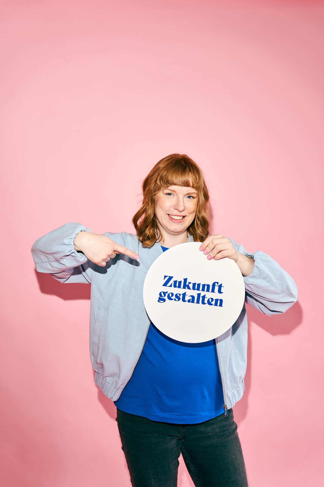 Personal-Brand-Designerin-Markenberatung-3 Personal Branding Portrait einer Frau die vor einem rosafarbenen Hintergrund steht, sie lacht in die Kamera und die Arme sind verschränkt. Obwohl sie die arme verschränkt hat, ist es ein offenes und authentisches Brandingfoto