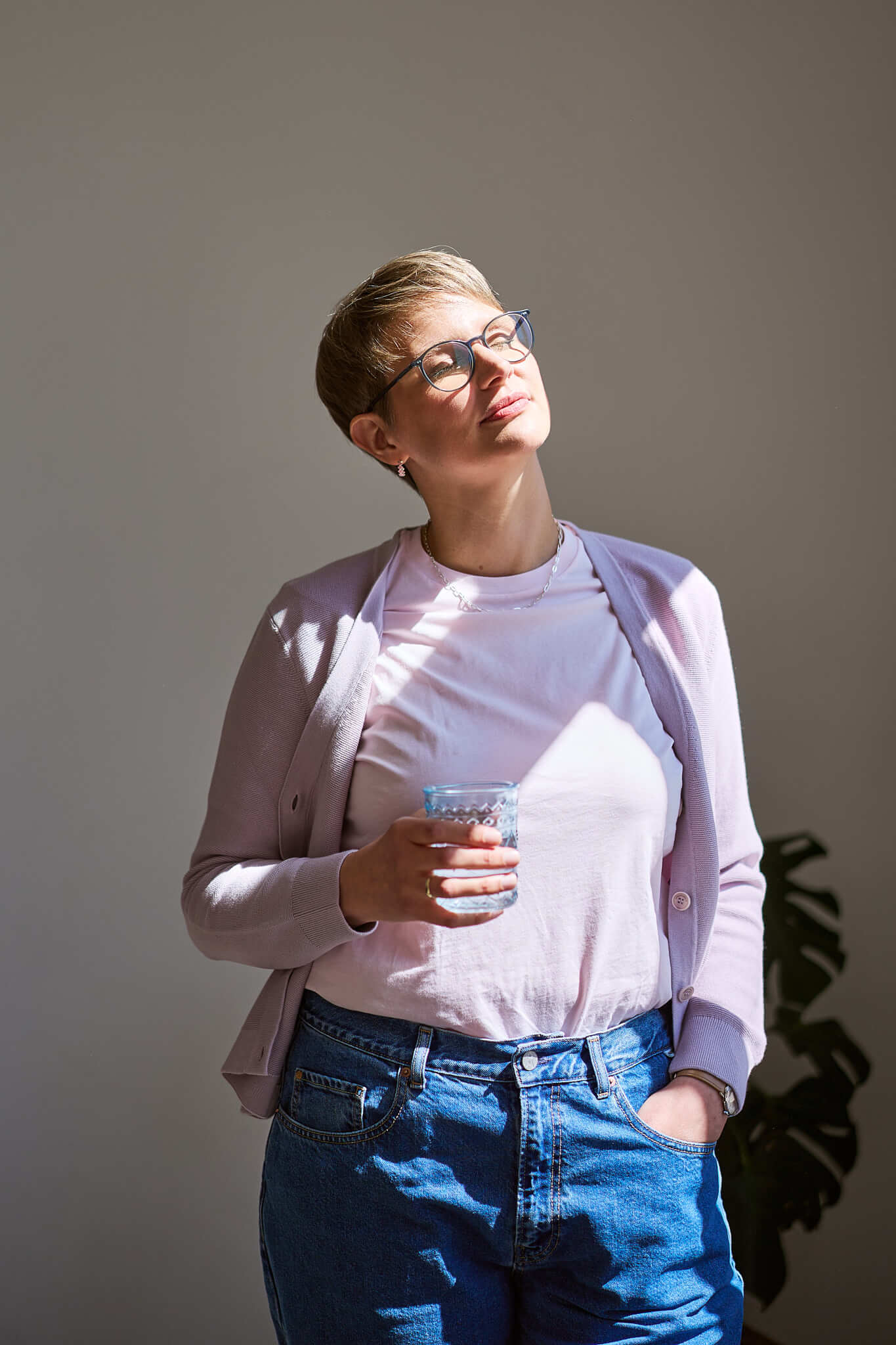 Eine Frau im schwarzen Outfit sitzt auf einem Hocker und schaut lachend in die Kamera