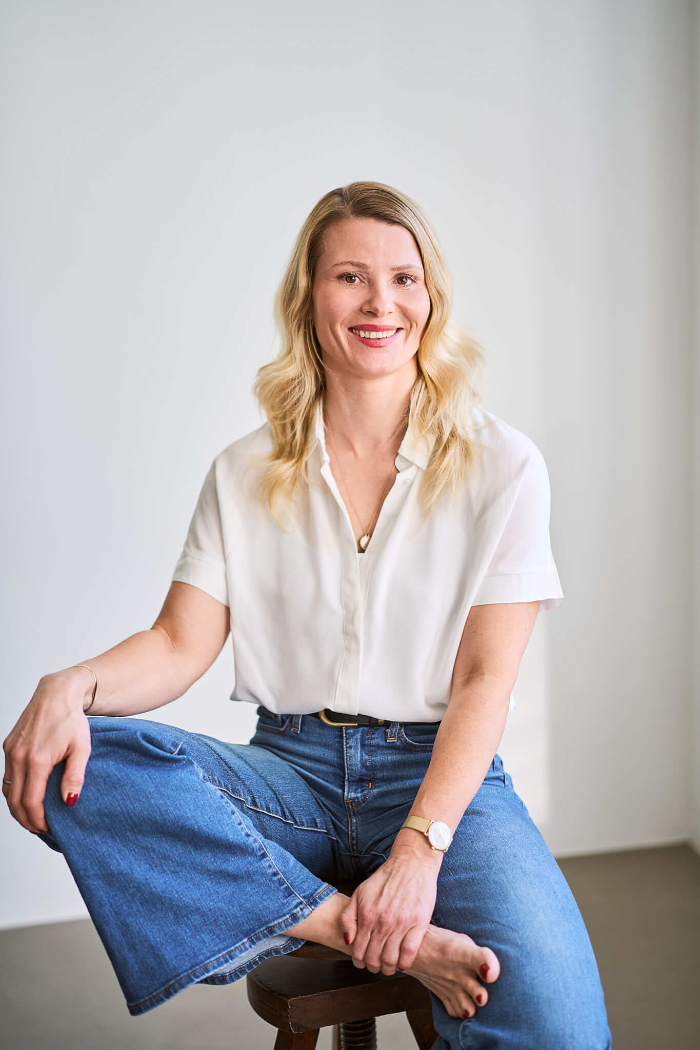 Eine Frau sitzt auf einem Hocker bei einer Portrait Session und schaut zur Seite
