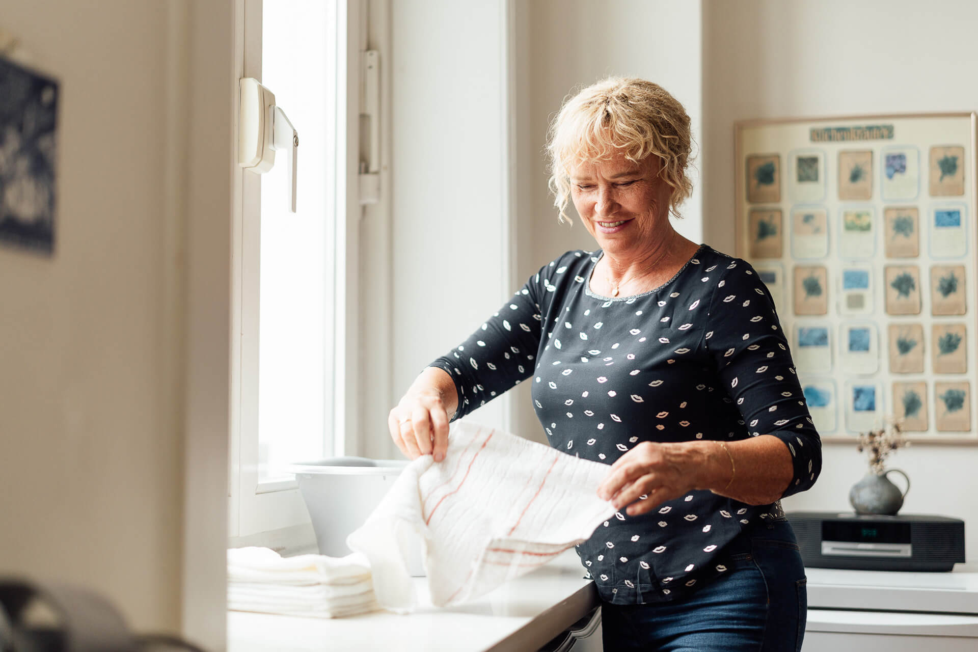 businessfoto-haeusliche-betreuung-waesche-zusammenlegen Betreuungskraft legt im Haushalt einer Seniorin Wäsche zusammen