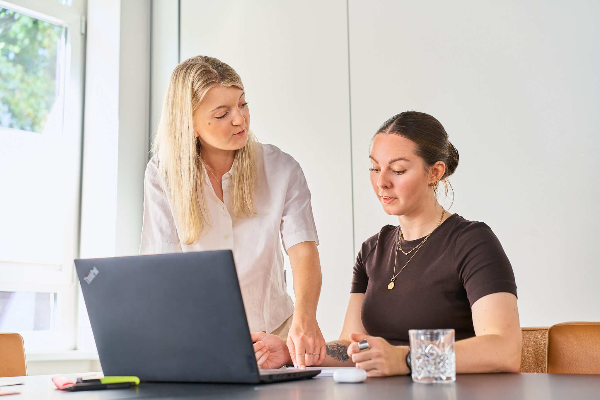 businessfotos-seo-agentur-arbeit-am-laptop Zwei Mitarbeiterinnen einer SEO-Agentur schauen gemeinsam auf einen Laptop